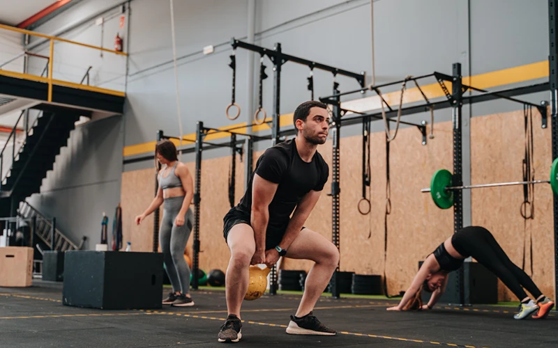 Treino de cross em box com kettlebell, argolas e caixas de salto